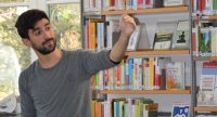 Mann steht vor Bücherregal, Quelle: DTF