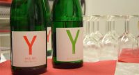 zwei grüne Weinflaschen auf roten Servietten neben auf den Kopf gestellten Weingläsern, Quelle: DTF