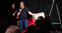 Mann gestikuliert und lächelt freundlich ins Mikrofon, Quelle: DTF