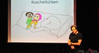 Mann steht neben Leinwand mit Karikatur mit dem Titel Kuscheltürken, Quelle: DTF