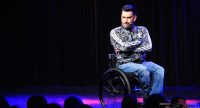 Mann im Rollstuhl vor Silhouette des Publikums, Quelle: DTF