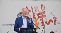 Mann im blauen Anzug sprechend ins Mikrofon vor Banner des Kinderfests, Quelle: DTF
