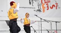 Jungs in traditioneller Kleidung tanzend auf der Bühne mit Banner des Kinderfests, Quelle: DTF