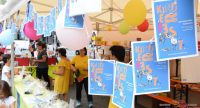 Menschen rund um einem grünen Tisch voller Preise mit kleinen Plakaten des Kinderfests, Quelle: DTF