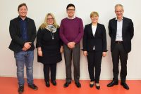 drei Männer und zwei Frauen stehen lächelnd vor einer weißen Wand, Quelle: DTF