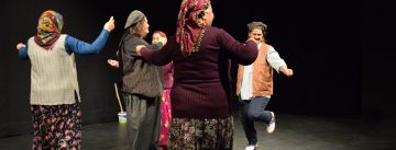 ältere Frauen auf der Bühne, zwei davon wie ein Mann angezogen, alle tanzen