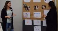 Quelle: DTF zwei junge Frauen stehen neben einer Metaplanwand mit verschiedenen Bildern und Zetteln, Quelle: DTF