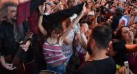 Musiker in traditioneller Kleidung schauen tanzender Frau im Publikum zu, Quelle: DTF