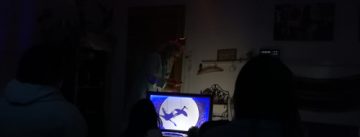 Blauer Bildschirm mit zwei Störchen im dunklen Raum