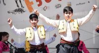 traditionell angezogene Jungs tanzend auf der Bühne mit Banner vom Kinderfest im Hintergrund, Quelle: DTF