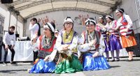 Mädchen in traditioneller Kleidung hingehockt vor der weißen Bühne, Quelle: DTF