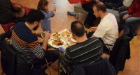 vier Menschen sitzend rund um einen Tisch essen gut beladene Teller, Quelle: DTF