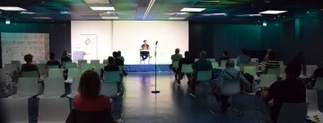 Hasnain Kazim sitzend auf dem Podium vor Silhouette des Publikums