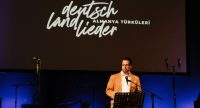 Ein Mann steht auf der Bühne und hält eine Rede, Quelle: DTF Stuttgart, Fotograf/in: Özlem Yavuz