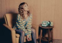 Frau in buntem Kleid auf einem Sessel sitzend, Quelle: Nilipek.