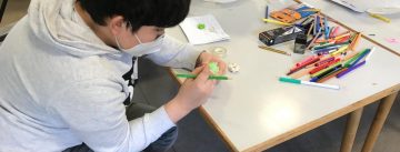 Ein Kind gestaltet mit Buntstiften ein Bild.