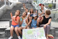 Fröhliche Kinder mit Eis und einer Stadtteilkarte sitzen auf einer Treppe, Quelle: DTF