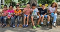 Kinder sitzen lachend auf einer Mauer, Quelle: DTF