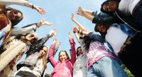 Gruppe junger Frauen steht im Kreis und streckt die Hände in die Höhe, Quelle: Canva