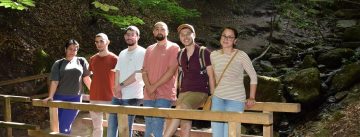 Junge Menschen stehen auf einer Brücke im Wald