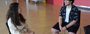Eine junge Frau und ein junger Mann sitzen sich gegenüber im Gespräch