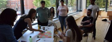 Workshopteilnehmer*innen stehen um einen Tisch mit Bastelmaterial