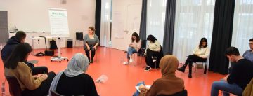 Workshopteilnehmende sitzen im Stuhlkreis und schreiben