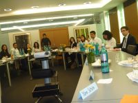 junge Menschen sitzen an Besprechungstischen, im Platz zwischen den Tischen ist ein Beamer, Quelle: DTF