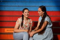 zwei junge Frauen sitzen lachend auf einer blauroten Treppe, Quelle: DTF