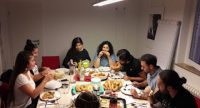 junge Menschen sitzen in der DTF Geschäftsstelle rund um einen bedeckten Tisch und essen zusammen, Quelle: DTF