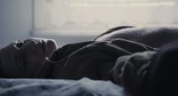 Eine Frau liegt mit ihrem Oberkörper auf einem Bett., Quelle: climate-change-still3