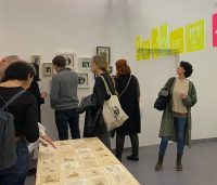 Mehrere Menschen besuchen eine Ausstellung und schauen sich die Kunstwerke an., Quelle: Aslimay Altay Göney